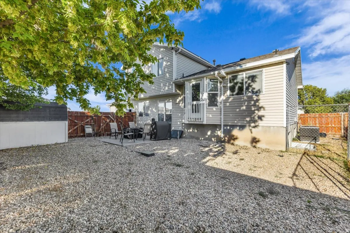 Backyard featuring a gravel surface, a raised patio, and an accessory shed