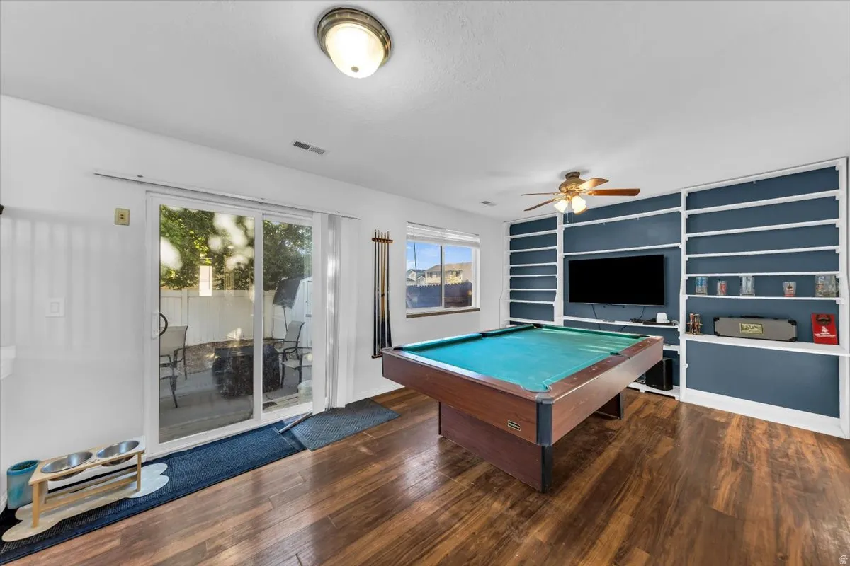 Wood-finish flooring, built-in shelving, ceiling fan with integrated lighting, glass sliding door, and a window providing natural light