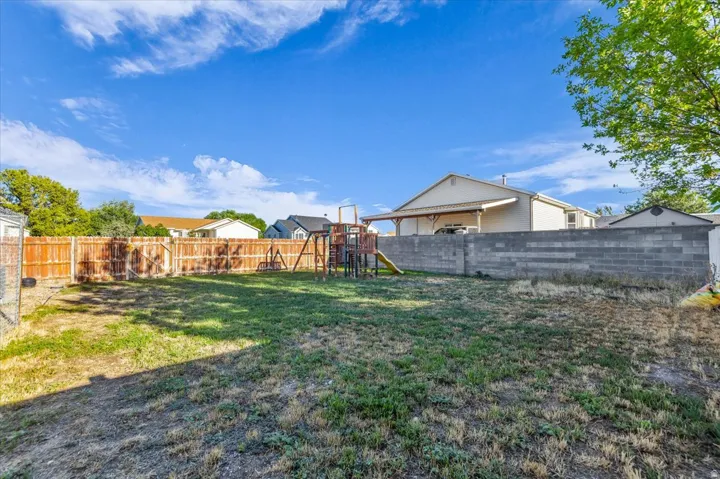 Expansive backyard featuring a wood privacy fence, concrete block wall, and mature trees
