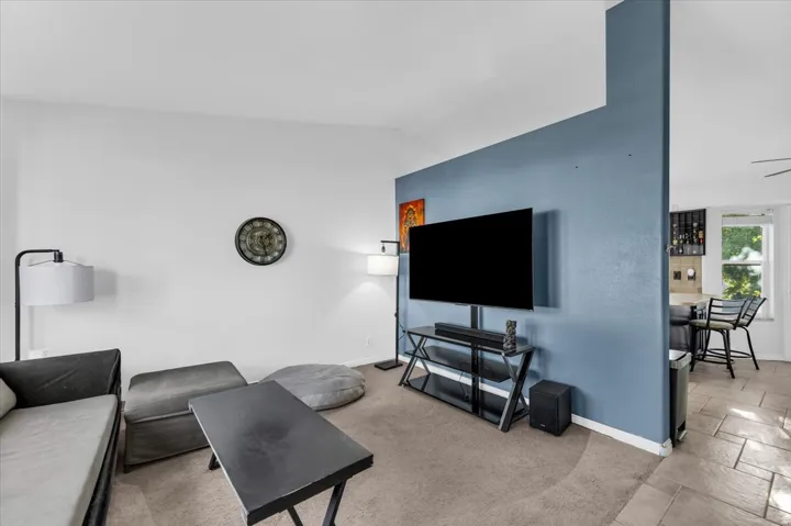 Carpeted living area with a partial wall featuring an accent color