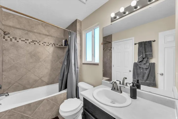 Bathtub with diagonal tiled surround, mosaic accent band, and built-in shelf