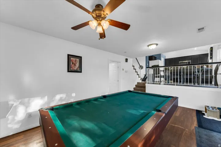 Wood-finish flooring with white walls and a ceiling fan