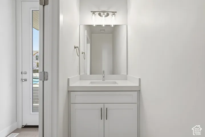 White shaker vanity with a single basin sink, white countertop, and brushed nickel hardware