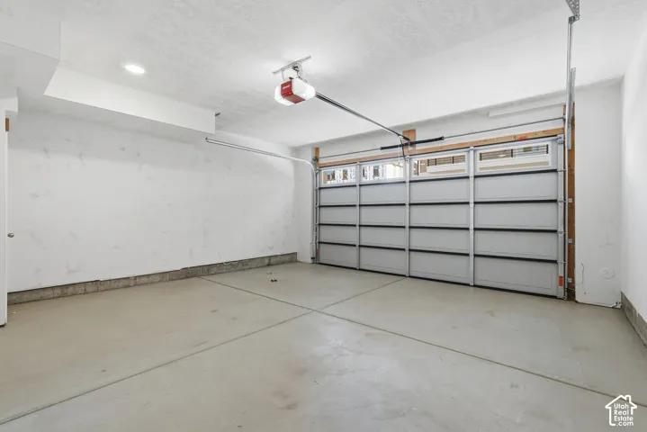 Attached garage with a sectional door, upper window panels, and a concrete floor