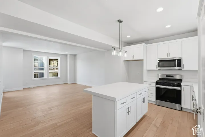Open-concept living space featuring wood-finish flooring, recessed lighting, and white cabinetry