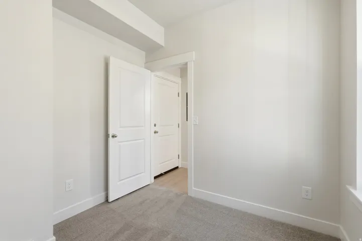 Neutral wall paint, plush carpet flooring, white trim, and solid core doors
