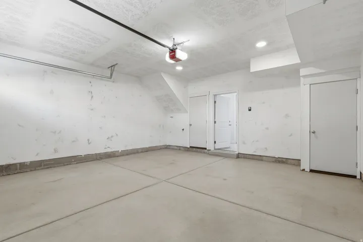Concrete flooring, two interior doors, recessed lighting, and a garage door opener