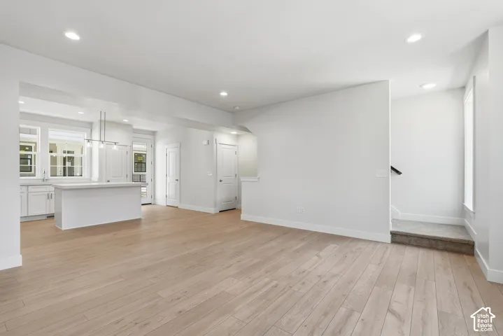 Open-concept living area with wood-finish flooring, recessed lighting, and a kitchen island with pendant lighting
