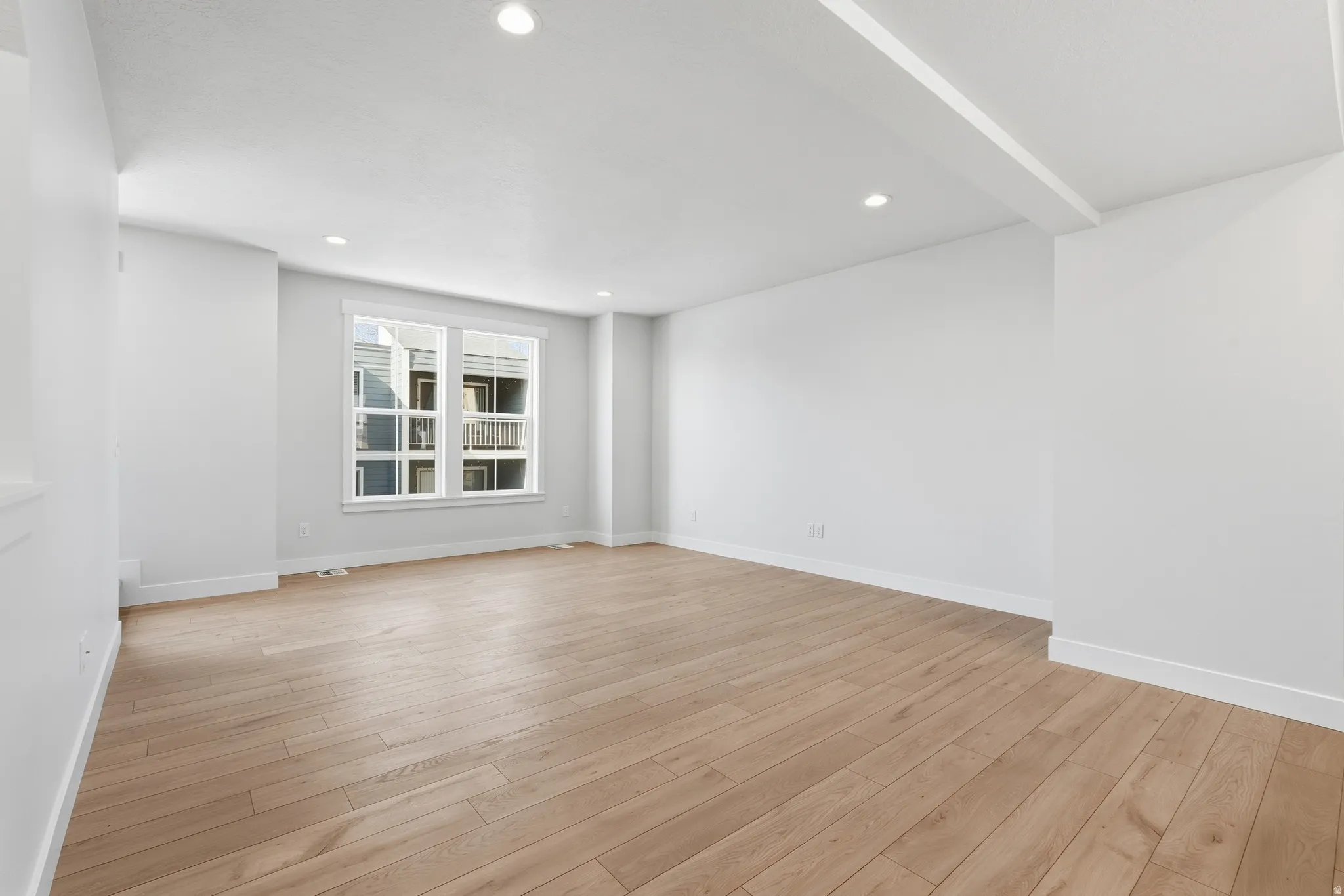 Spacious room featuring wood-finish flooring, recessed lighting, and a large window