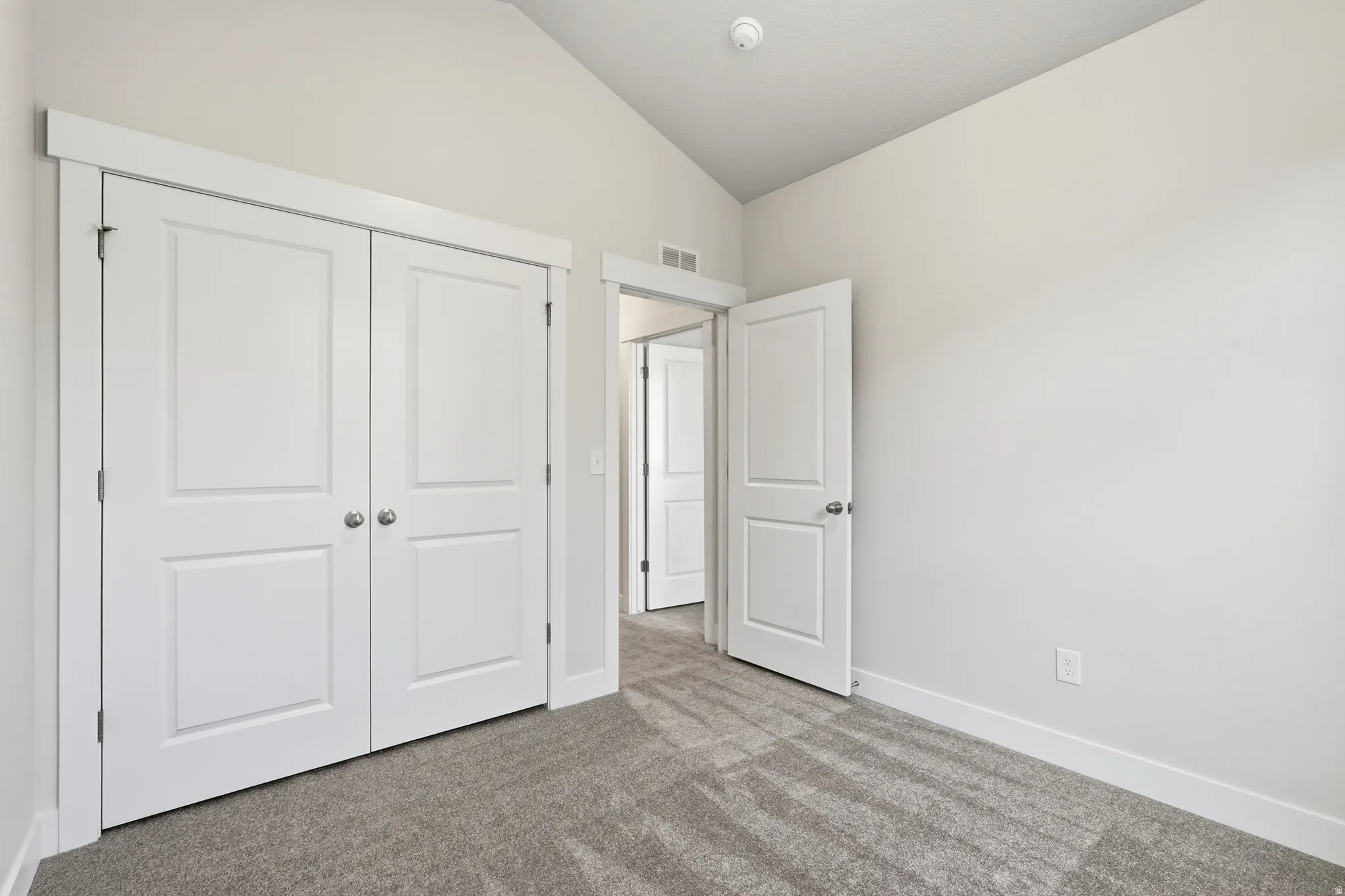 Bright bedroom featuring dual white panel closets with polished hardware, neutral wall finishes, and plush carpeting throughout