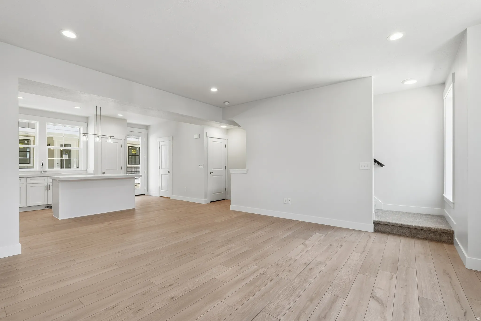 Open-concept living area with wood-finish flooring, recessed lighting, and a kitchen island with pendant lighting