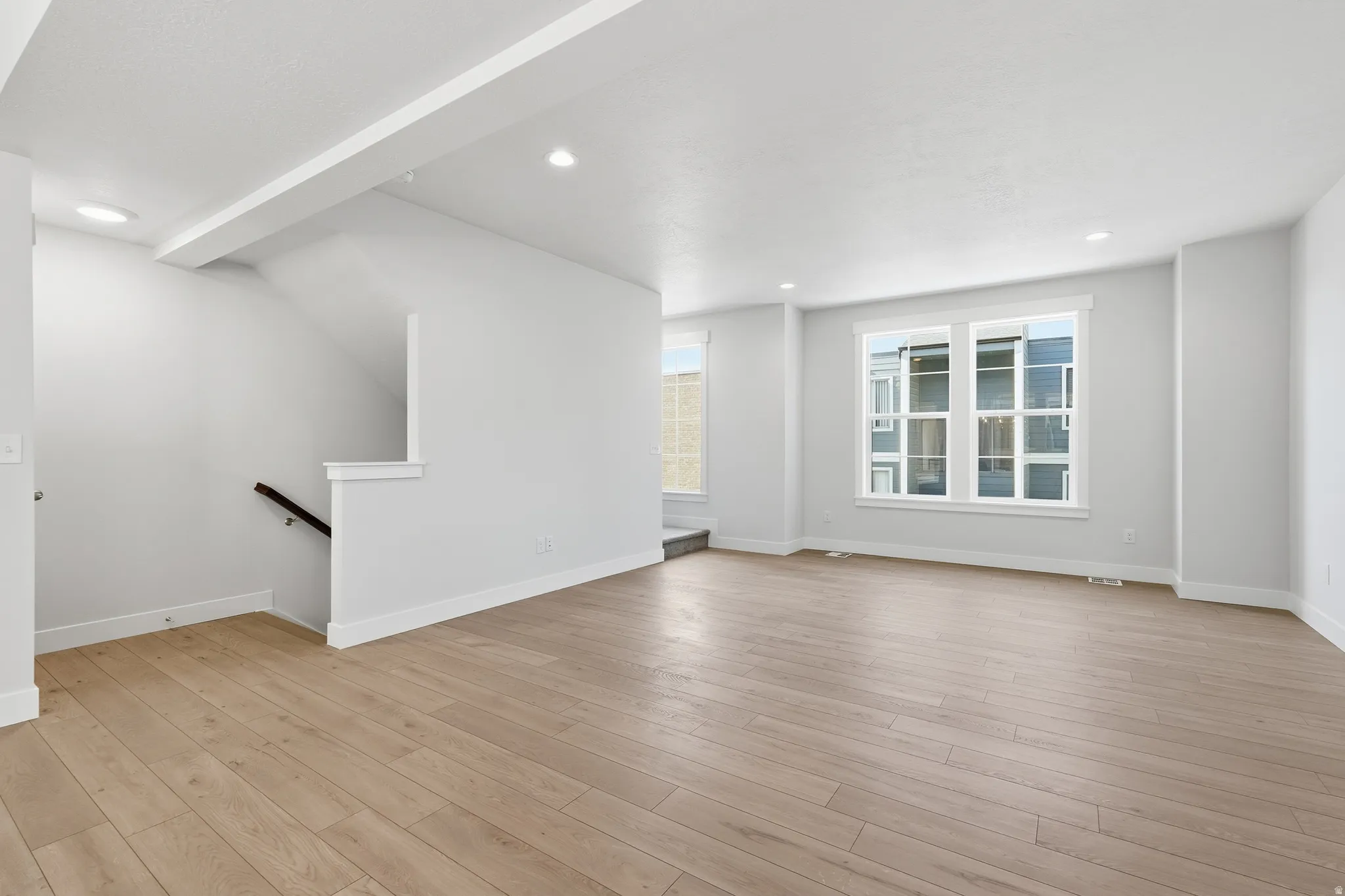 Recessed lighting illuminates wood-finish flooring throughout the open layout
