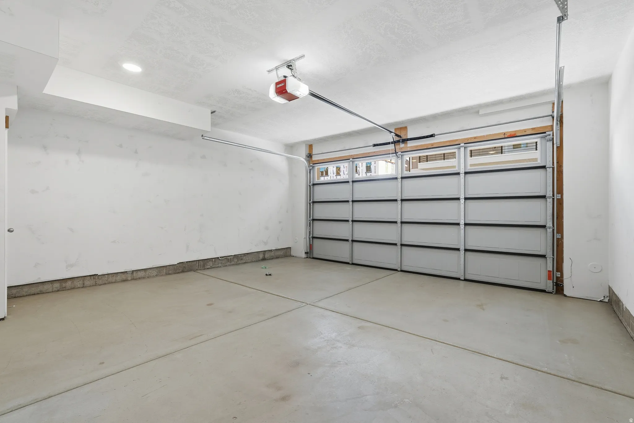 Attached garage with a sectional door, upper window panels, and a concrete floor