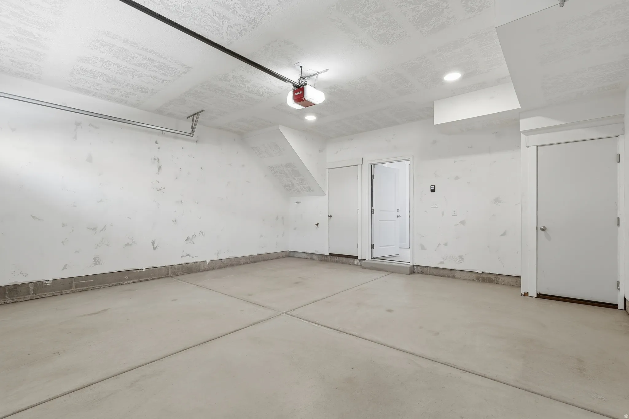 Concrete flooring, two interior doors, recessed lighting, and a garage door opener