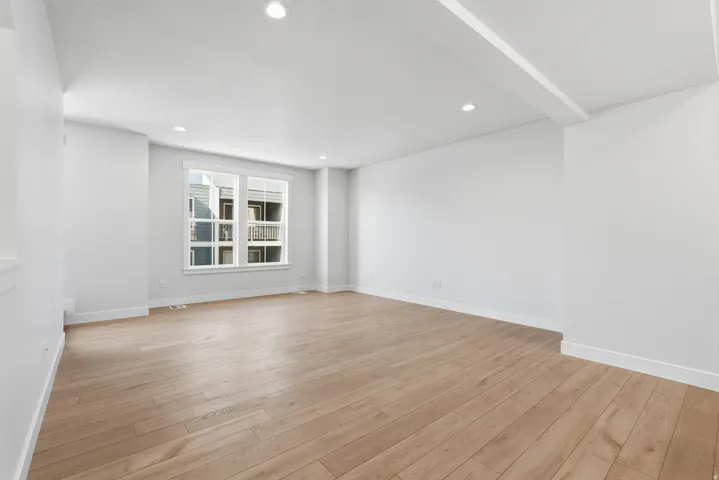 Spacious room featuring wood-finish flooring, recessed lighting, and a large window