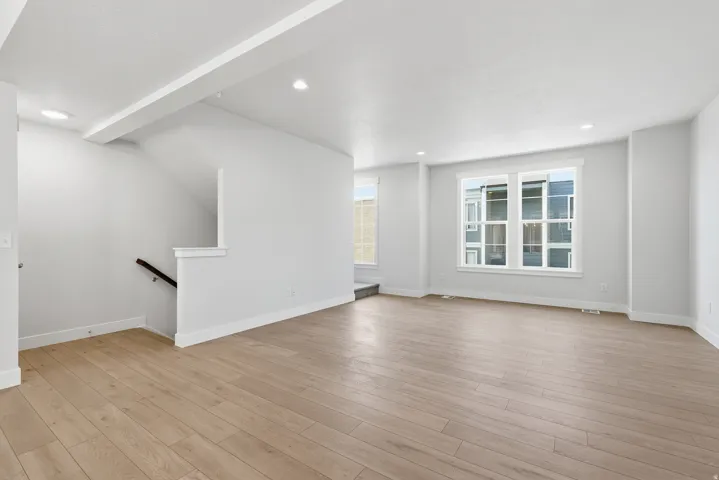 Recessed lighting illuminates wood-finish flooring throughout the open layout