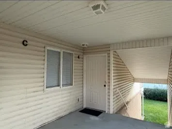 Covered entry with vinyl siding and a paneled door