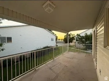 Covered outdoor patio with a flat ceiling, white railing, and exterior wall siding