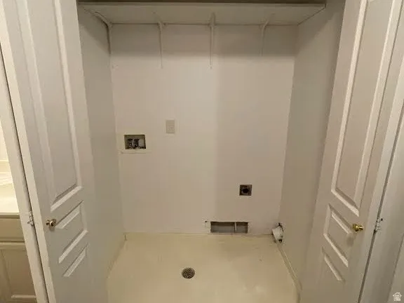 Utility closet with bifold doors, integrated shelving, and a floor drain