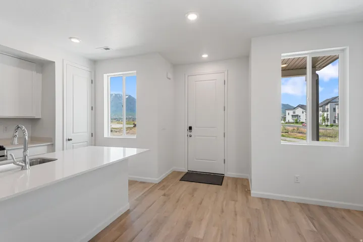 Open-concept area featuring light wood-finish flooring, recessed lighting, and white walls