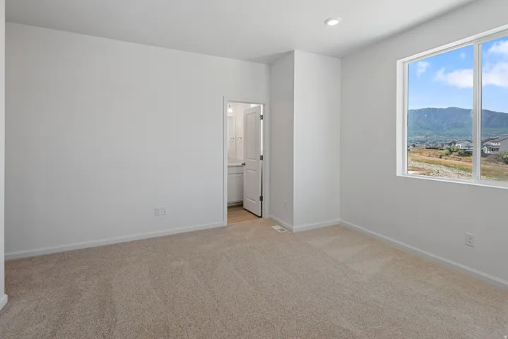 Plush carpet flooring, recessed ceiling lighting, and a large window providing expansive mountain scenery