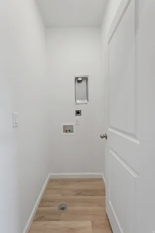 Dedicated laundry area with wood-finish flooring and a white paneled door