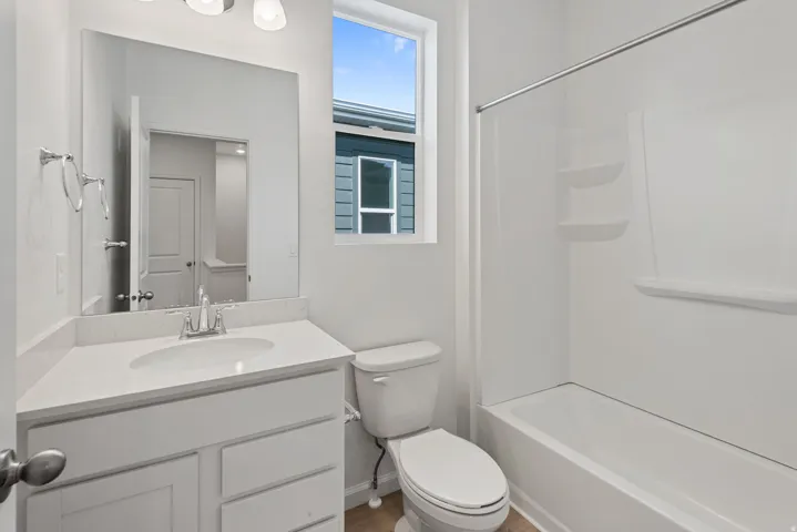 Bathroom featuring a single vanity with stone-finish countertop, undermount sink, and white cabinetry