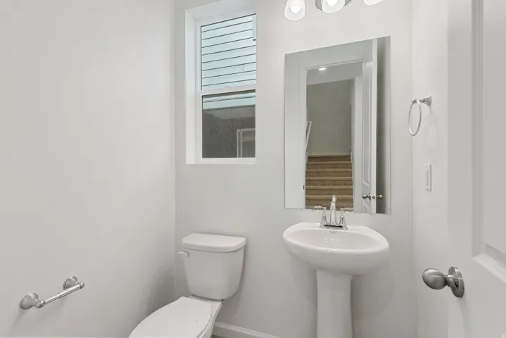 White pedestal sink, chrome faucet, wall-mounted mirror, and overhead vanity light fixture