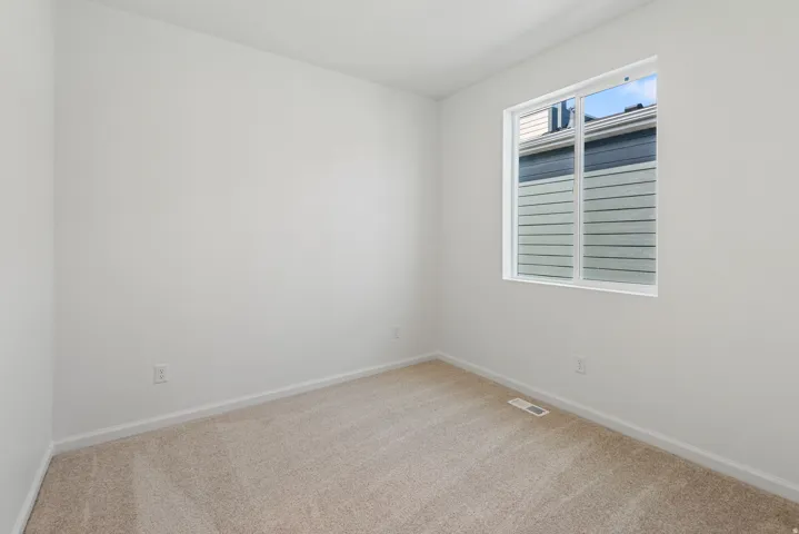 Neutral-toned carpeting, white walls, and a white-framed window