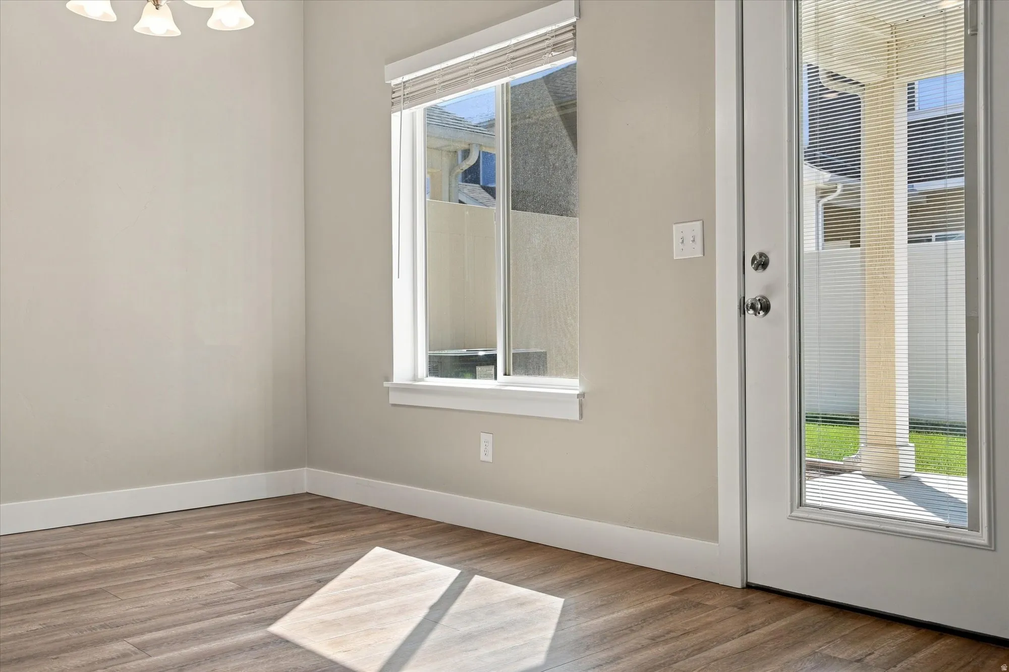 Wood-finish flooring, neutral wall tones, transom window, and a full-light door with integrated blinds