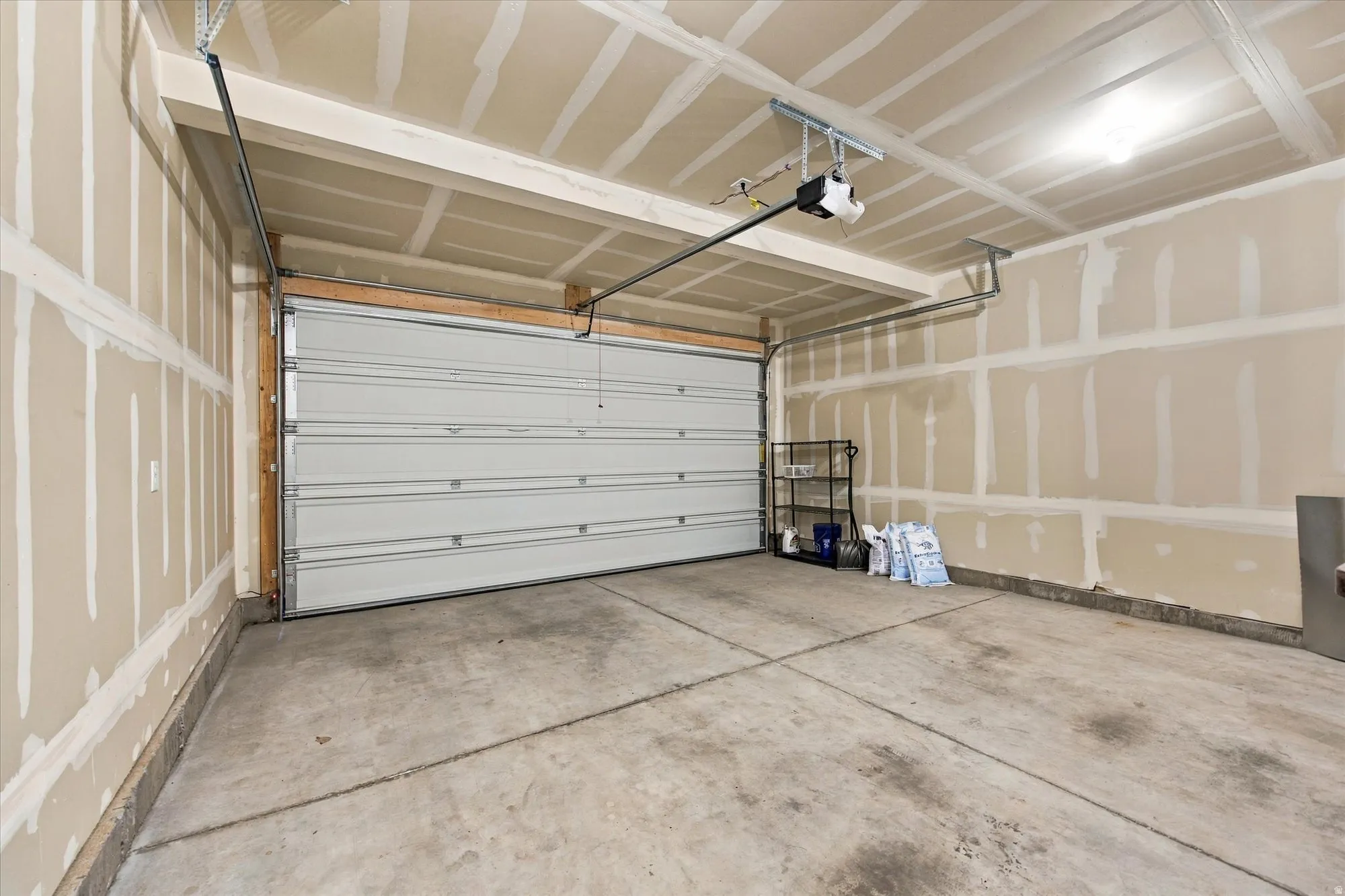 Attached garage featuring an automatic opener, concrete flooring, and an overhead light fixture
