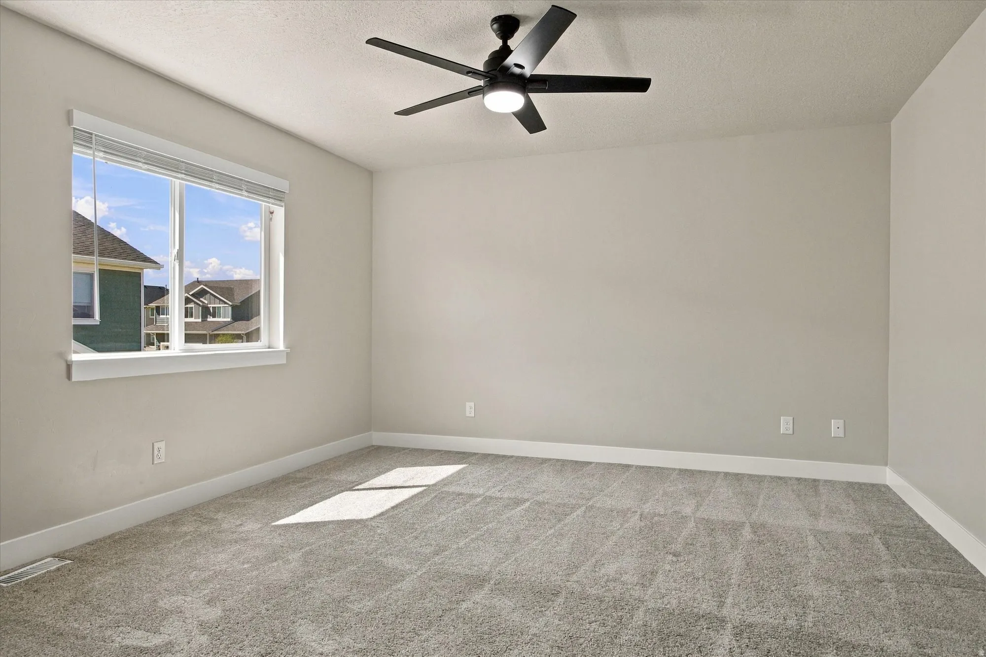 Room with neutral wall paint, gray carpet flooring, white trim, and a ceiling fan with integrated lighting