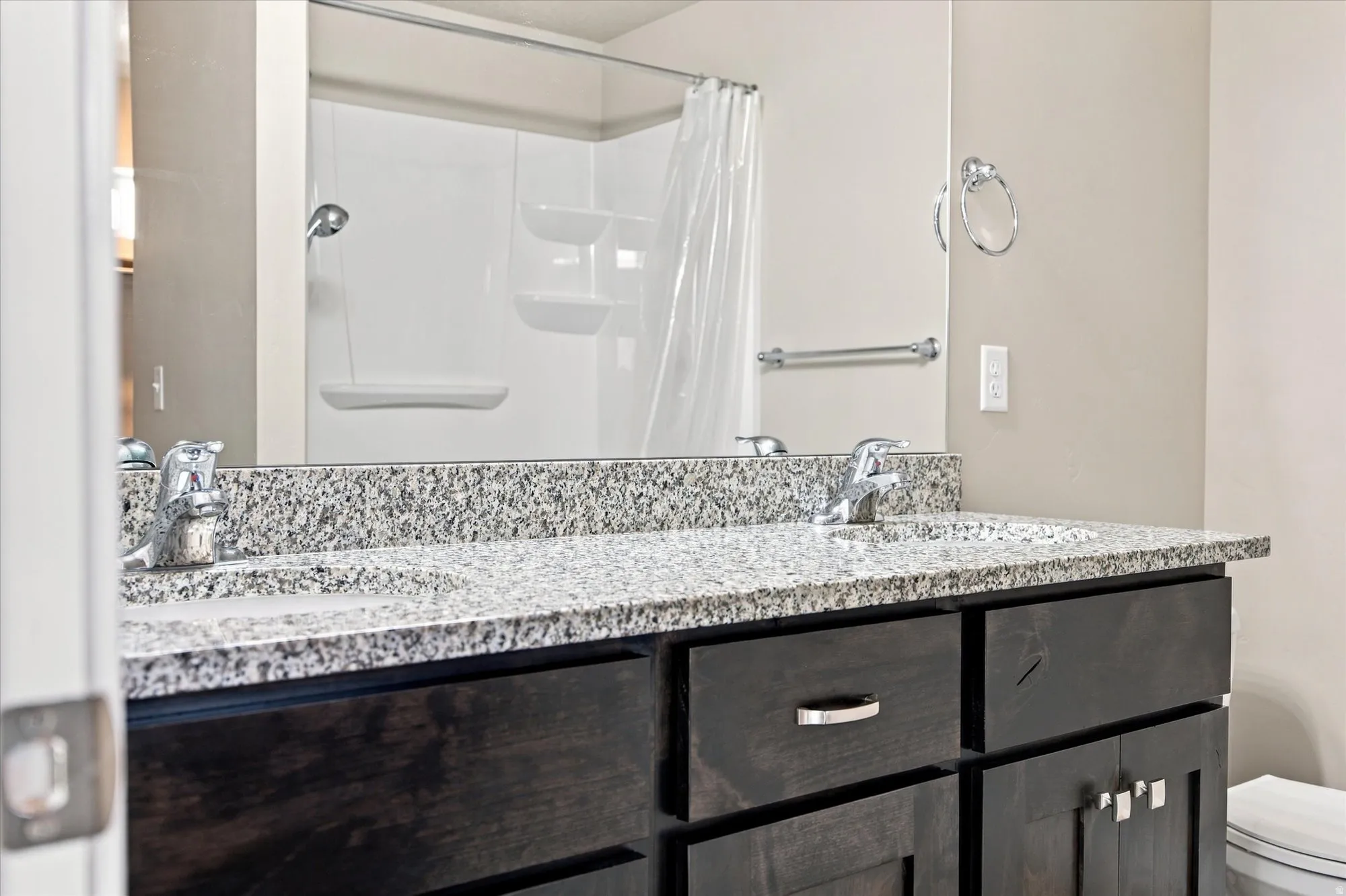 Dual vanity with integrated sinks, speckled countertop, and dark wood-finish cabinetry