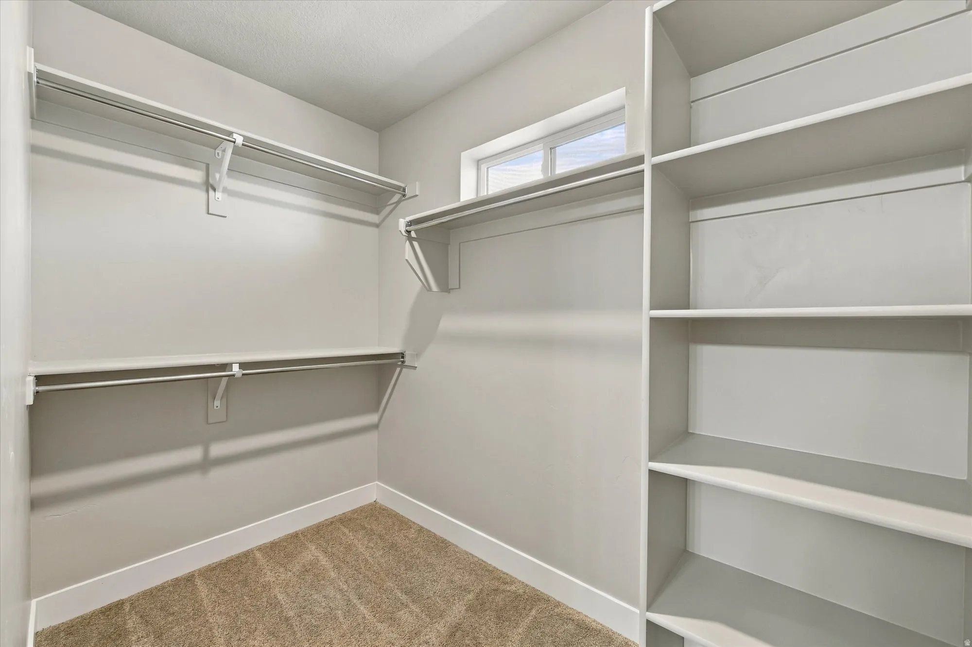 Built-in shelving, multiple hanging rods, and a high window provide storage and natural illumination