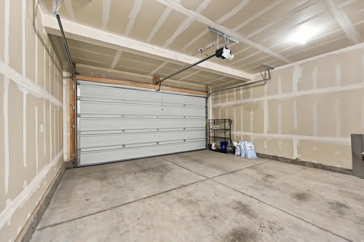 Attached garage featuring an automatic opener, concrete flooring, and an overhead light fixture