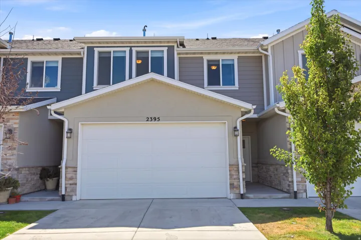 Contemporary townhouse exterior featuring a two-car garage, stone and siding accents, and a covered entry