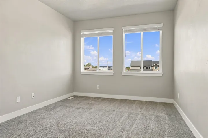 Dual windows with white trim, plush gray carpeting, and neutral wall tones