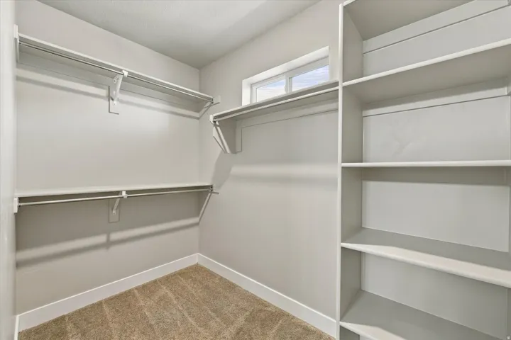 Built-in shelving, multiple hanging rods, and a high window provide storage and natural illumination