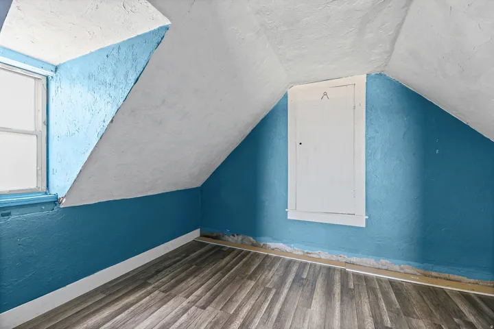 Room with wood-finish flooring, a window, and a built-in access panel