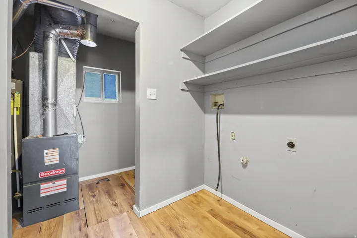 Utility area with wood-finish flooring, built-in shelving, and a Goodman furnace