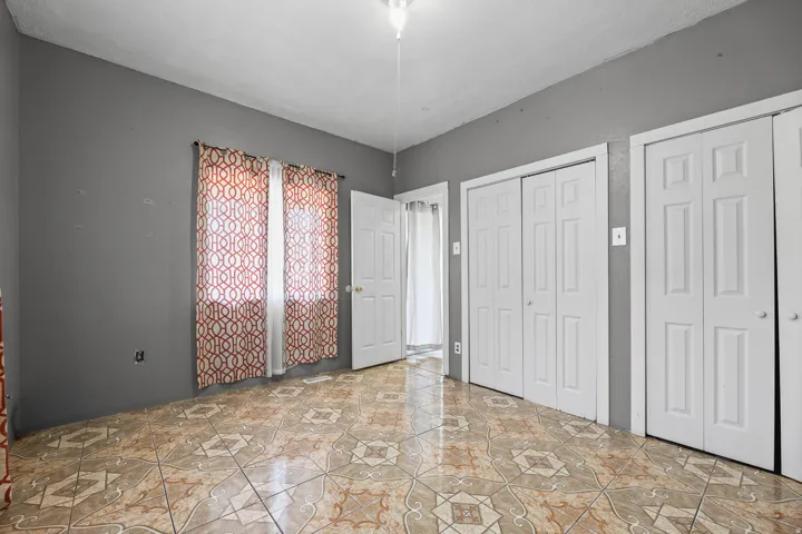 Tile flooring with a geometric pattern, neutral wall paint, and multiple bi-fold closet doors