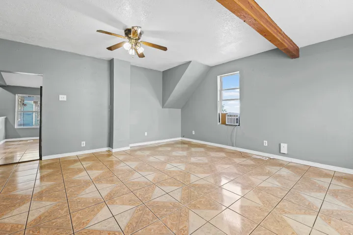 Patterned tile flooring, ceiling fan, exposed beam, and window unit