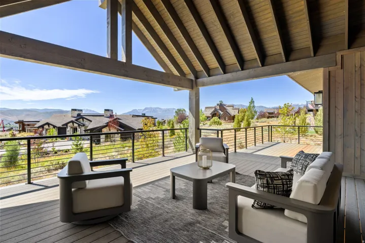 Expansive covered deck featuring exposed wood beams, wood-finish decking, and cable railings