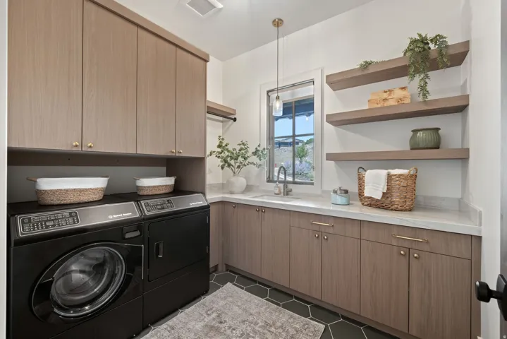 Wood-finish cabinetry with brass hardware, undermount sink, floating wood-finish shelving, and hexagon floor tiling