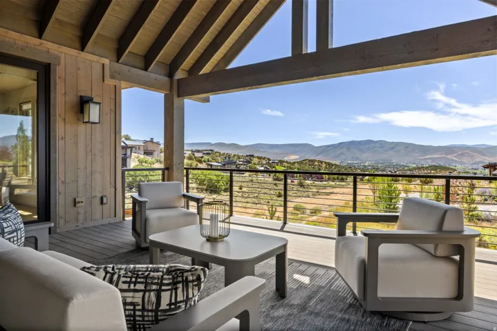 Expansive covered deck featuring a wood-plank ceiling, exposed wood beams, and a cable railing system