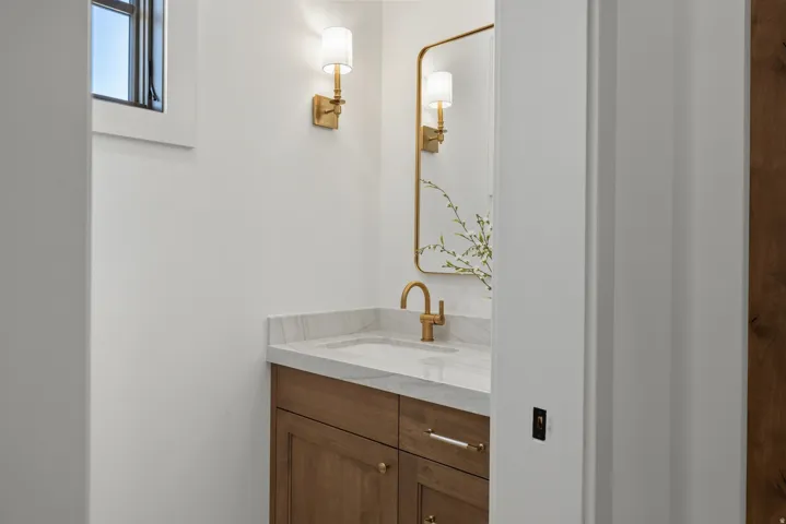 Built-in vanity with a stone-finish countertop, undermount sink, and wood-finish cabinetry