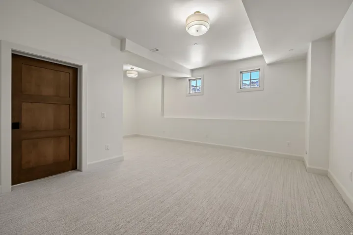 Neutral-toned carpeting, two windows, and overhead lighting fixtures