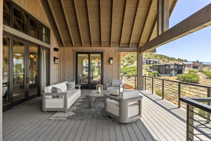 Expansive covered deck featuring a wood-plank ceiling, wood-finish siding, and multiple sets of glass panel doors