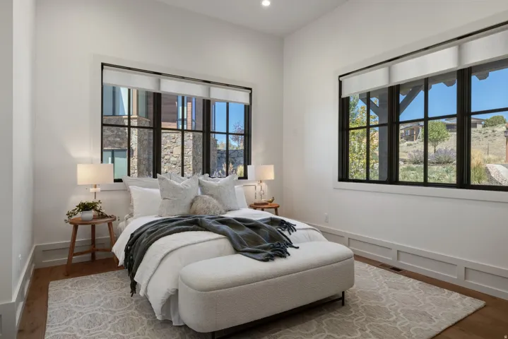 Wood-finish flooring, white walls, black-trimmed windows, recessed lighting, and decorative wall paneling