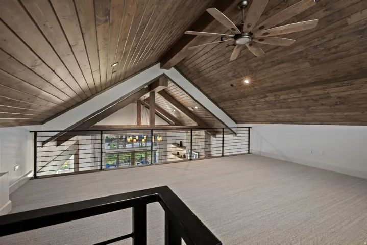 Vaulted wood-paneled ceiling with exposed beams, recessed lighting, and a multi-blade ceiling fan